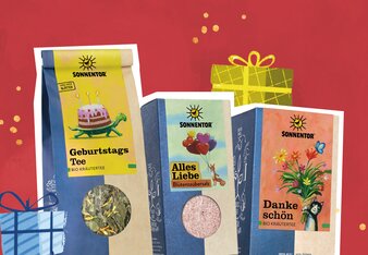Illustration mit drei Produkten als Geschenk auf rotem Hintergrund mit Geschenkpackung. | © SONNENTOR